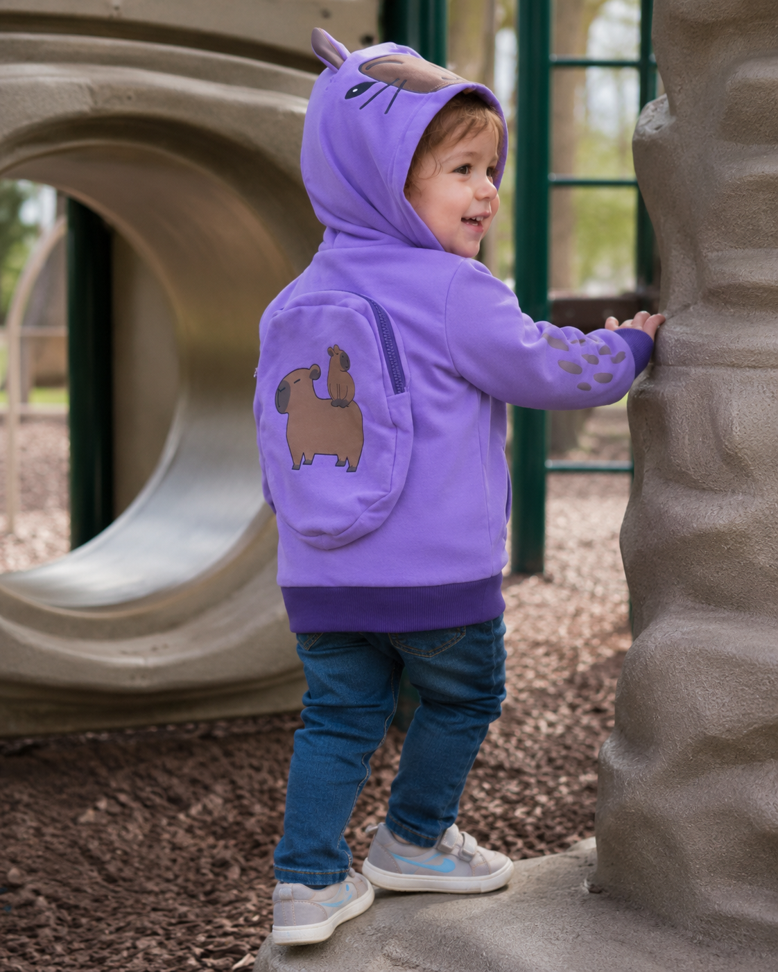 Child wearing the Lavender Sky backpack hoodie at a playground